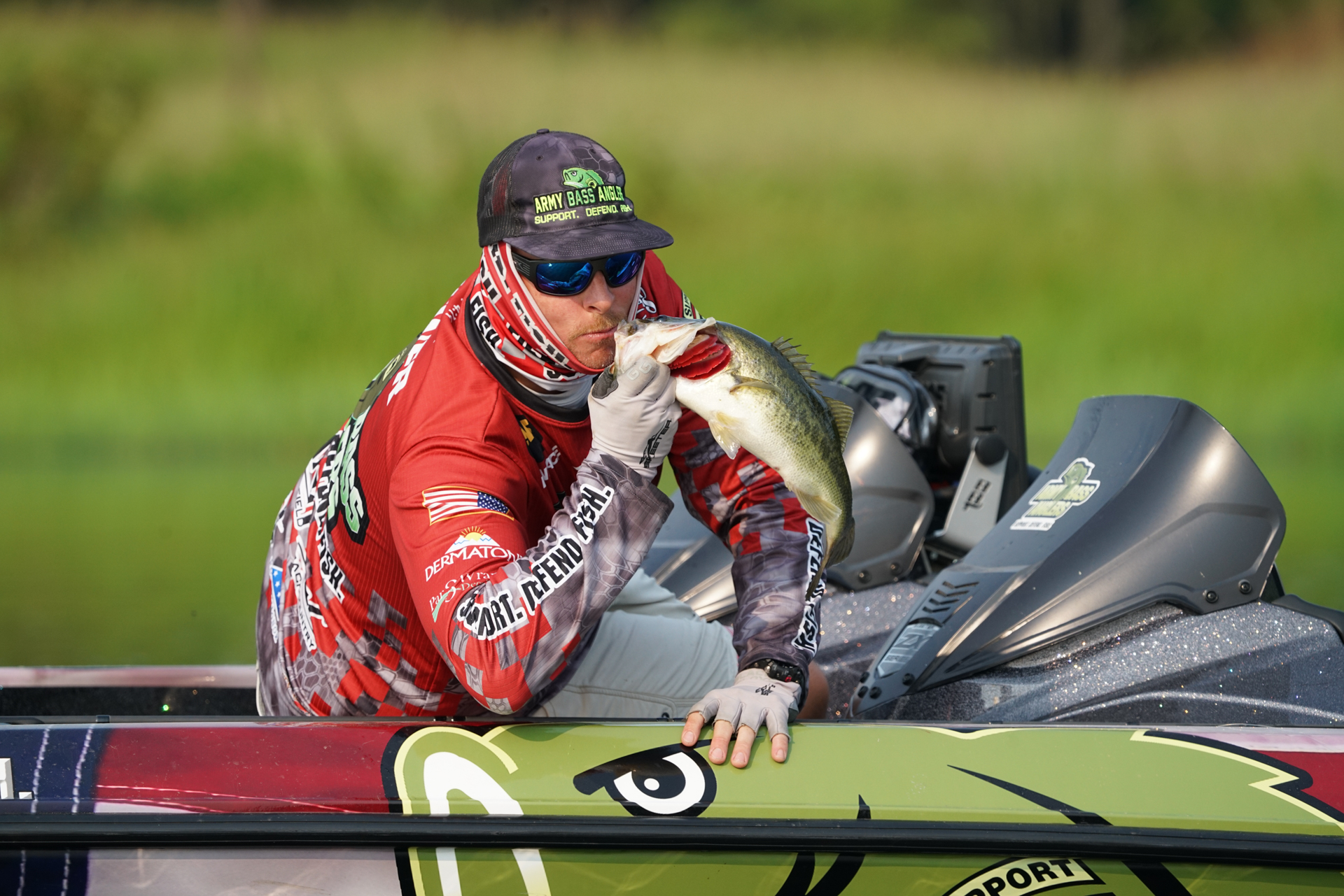 An image of an army veteran, firefighter, and angler Cole Brewer, kissing a fish for the camera just before he releases him back into the waters at the Fishing for Freedom Texas Tournament.